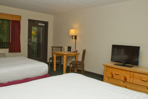 guest room with two queen beds and door to balcony with forest view